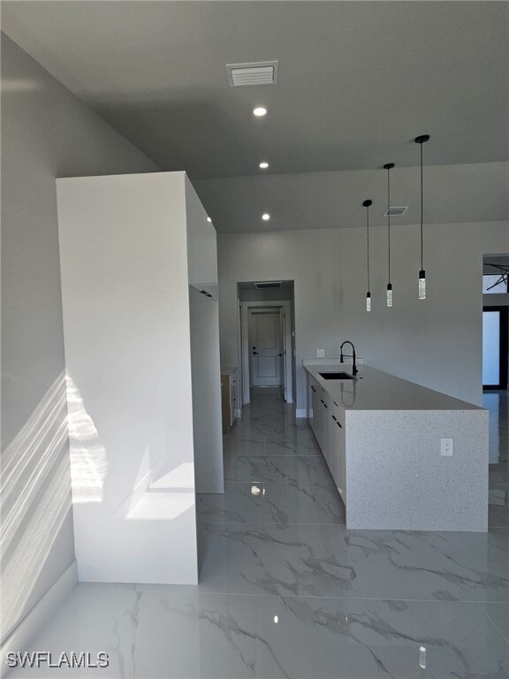 Kitchen with pendant lighting, white cabinetry, an