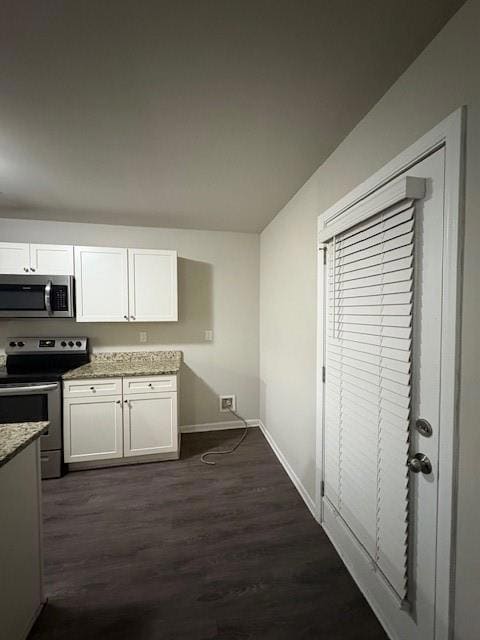 Kitchen with range, dark wood-type flooring, white cabinets, and light stone countertops