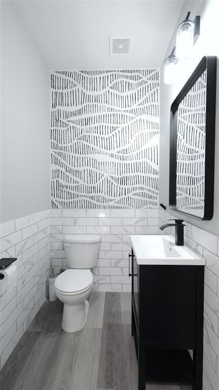 Bathroom featuring tile walls, vanity, and wainsc