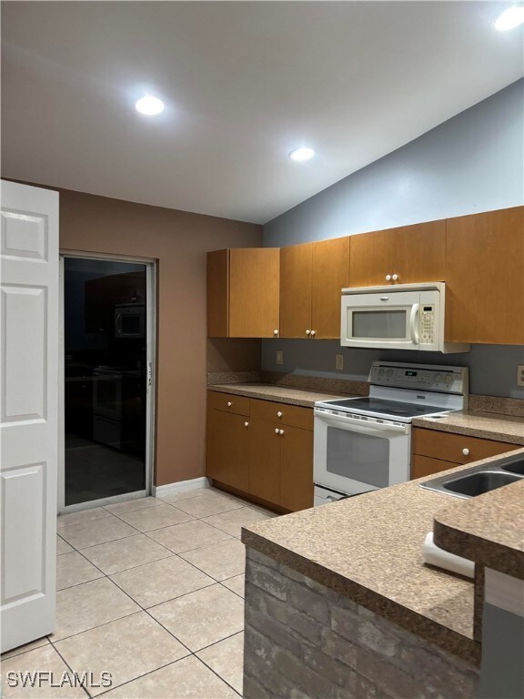 Kitchen with white appliances, lofted ceiling, lig