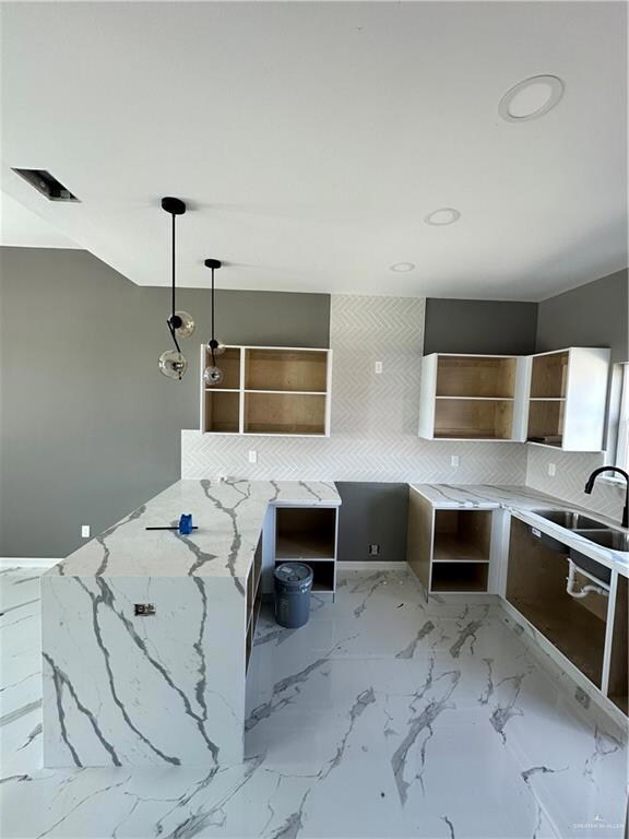 Kitchen featuring tile flooring, decorative light fixtures, light stone counters, sink, and white cabinets