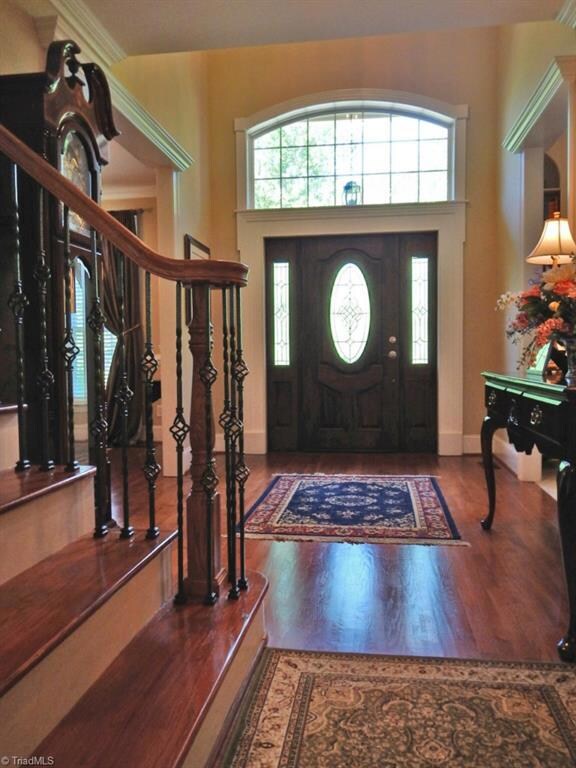 The 2-story Entry features a beautiful wood door & side panels with leaded glass inserts, hardwood floors & stairs with custom wrought-iron railing & a catwalk between Entry & upper level Family Room.