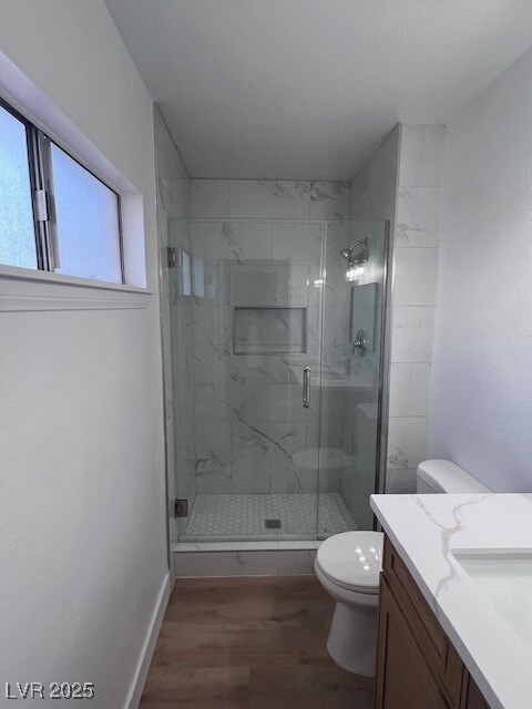 Full bathroom with dark wood-type flooring, a marble finish shower, and vanity