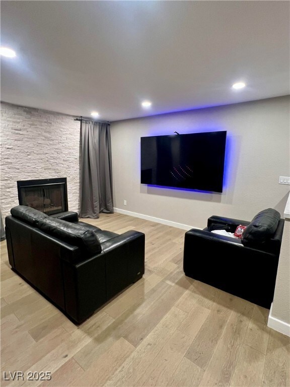 Living room with baseboards, a fireplace, light wo