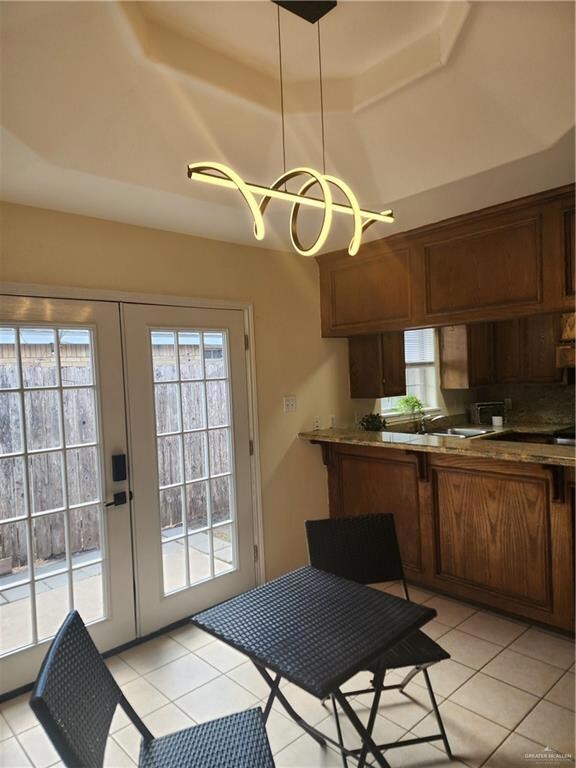 Kitchen featuring french doors, a raised ceiling, and hanging light fixtures