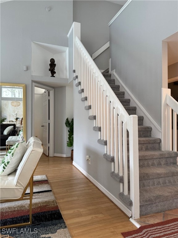 Staircase with wood finished floors and a high cei