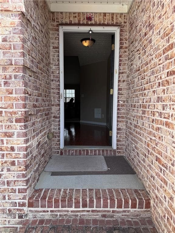 Doorway to property featuring brick siding