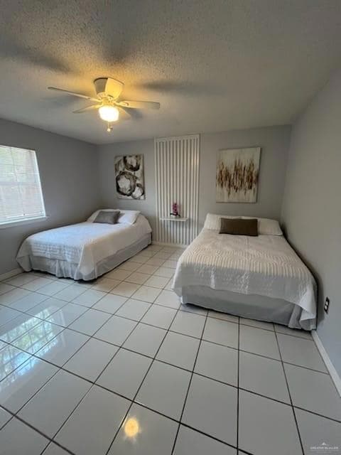 Bedroom with light tile patterned flooring, a textured ceiling, and a ceiling fan
