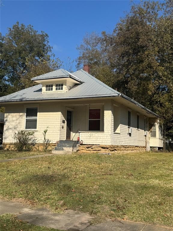 View of front of home featuring a front lawn, covered porch, and a metal roof