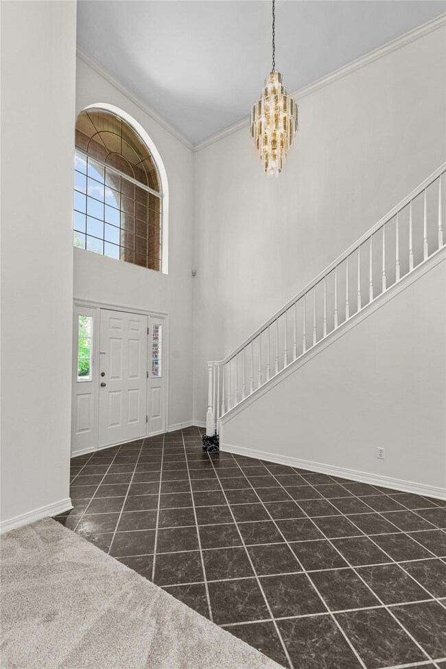 Foyer featuring an inviting chandelier, crown mold