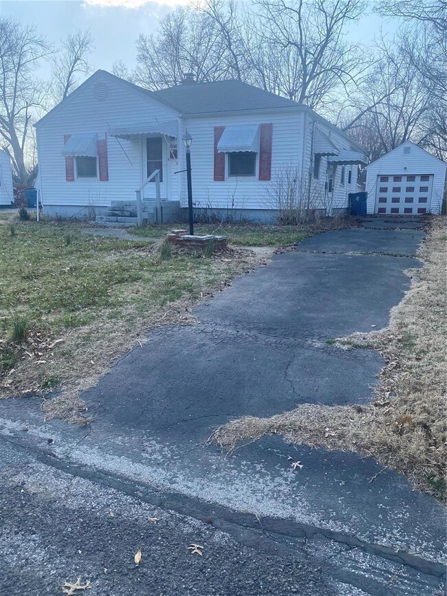 View of front of home featuring aphalt driveway, a detached garage, and an outdoor structure