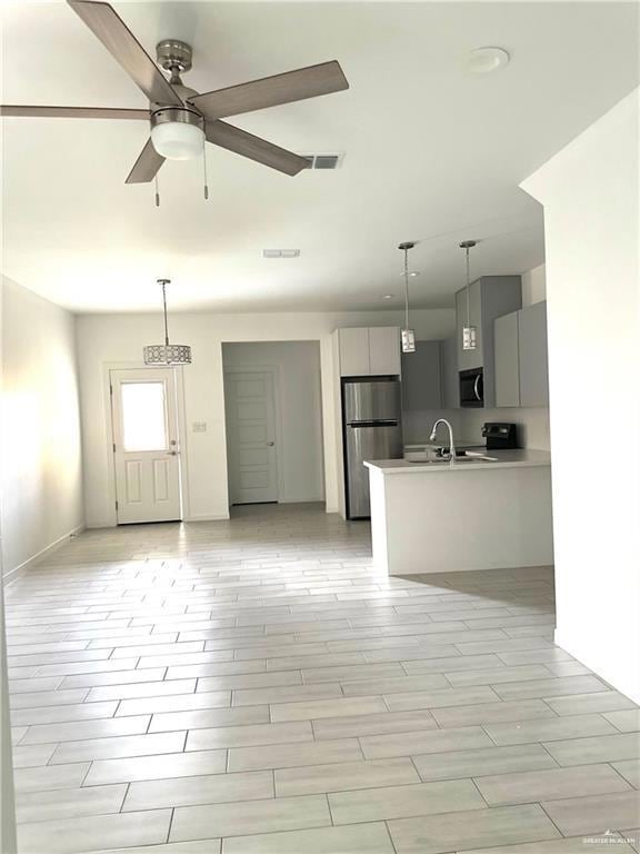Kitchen with gray cabinetry, open floor plan, decorative light fixtures, a peninsula, and light countertops