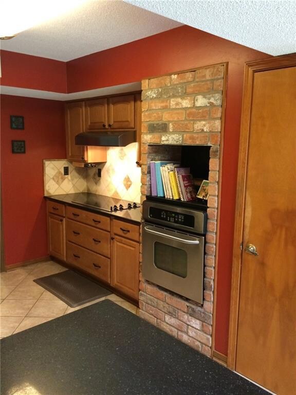 View of kitchen with stainless steel oven, cooktop