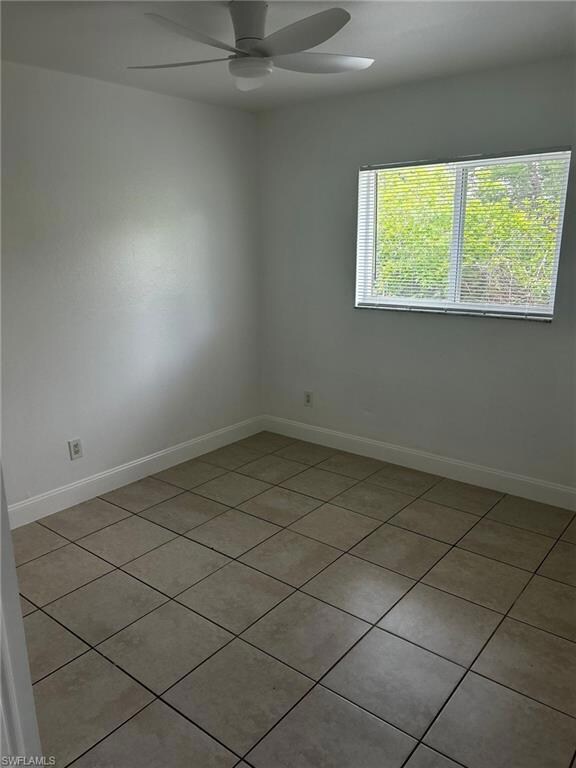Unfurnished room featuring a ceiling fan, light tile patterned floors, and baseboards