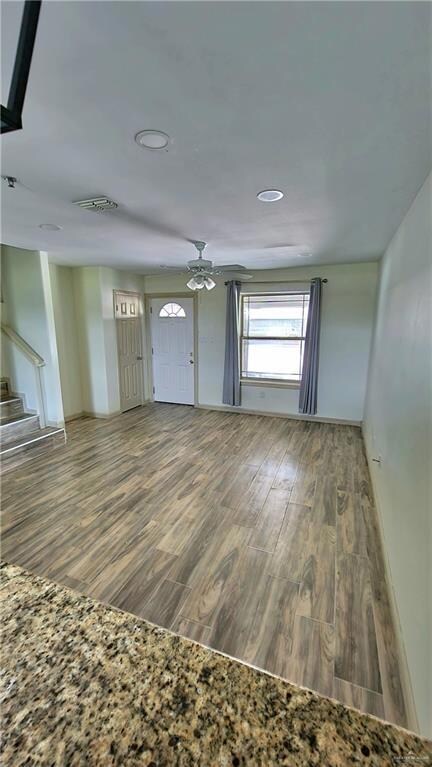 Unfurnished living room featuring wood finished floors and a ceiling fan