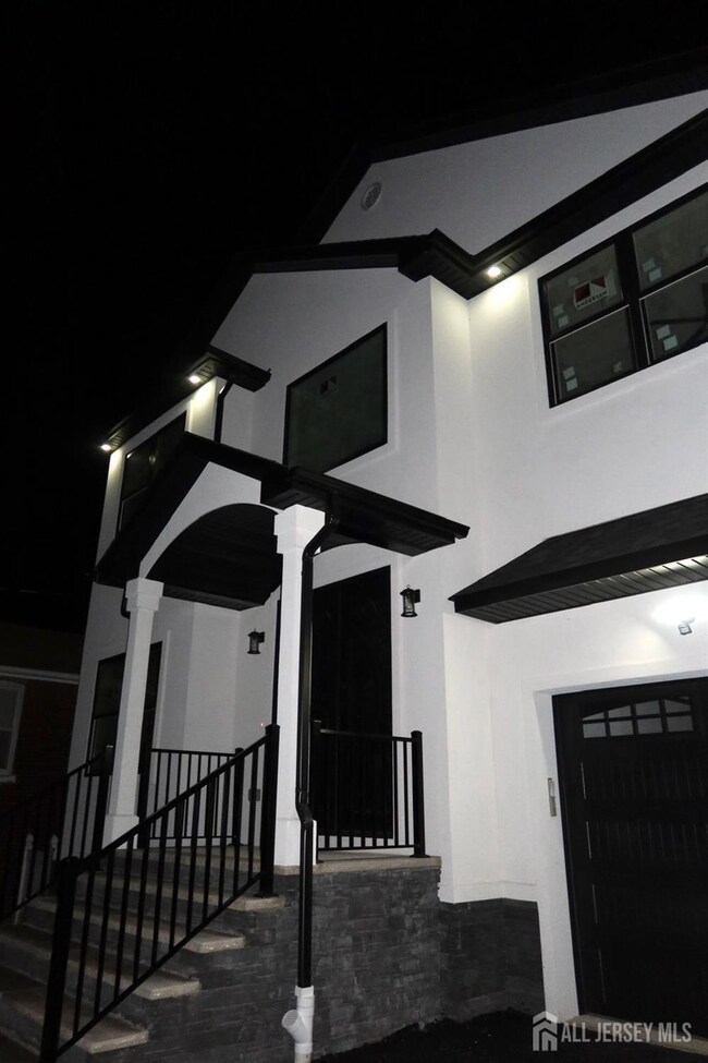 exterior entry at night with stucco siding, a garage, and covered porch