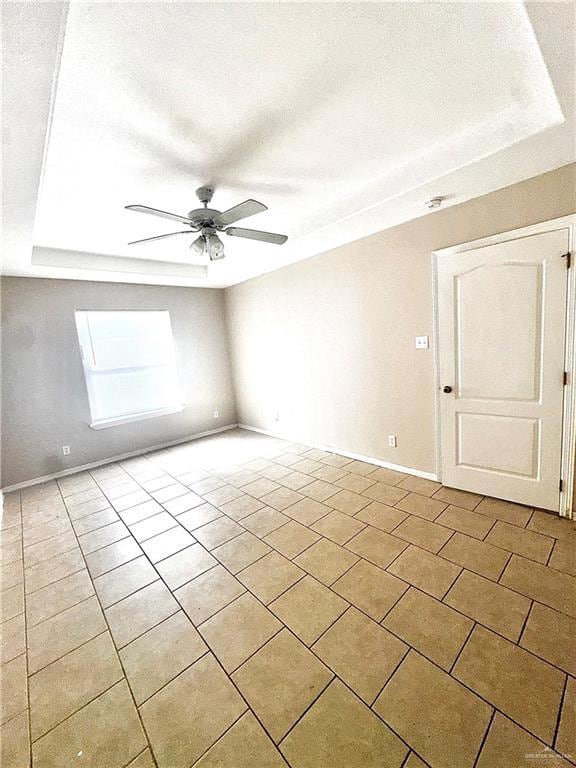 Tiled empty room featuring baseboards and a ceiling fan