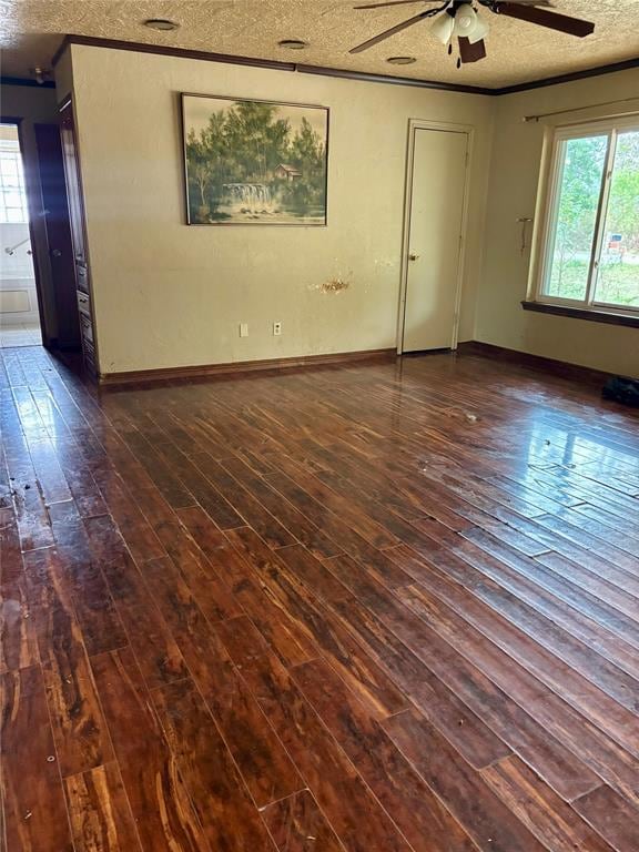 Empty room with dark wood-type flooring, a textured ceiling, and a ceiling fan