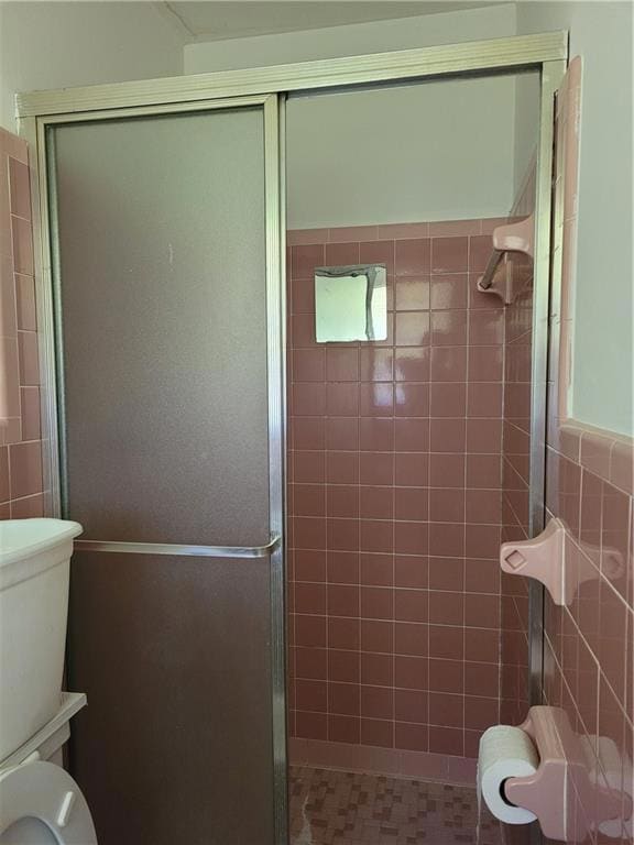 Bathroom with walk in shower, tile walls, and toil