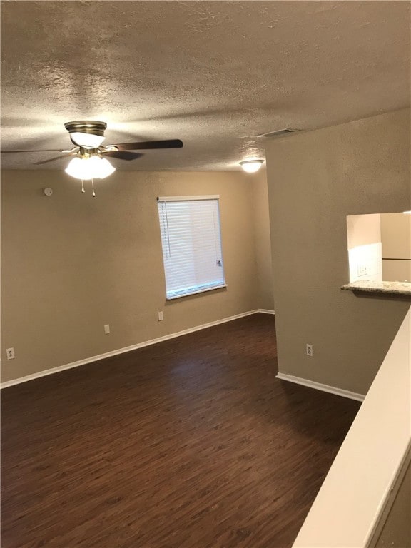 Empty room with dark wood-style floors, a textured