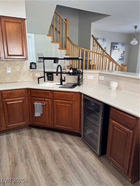 Kitchen with beverage cooler, a sink, light wood f