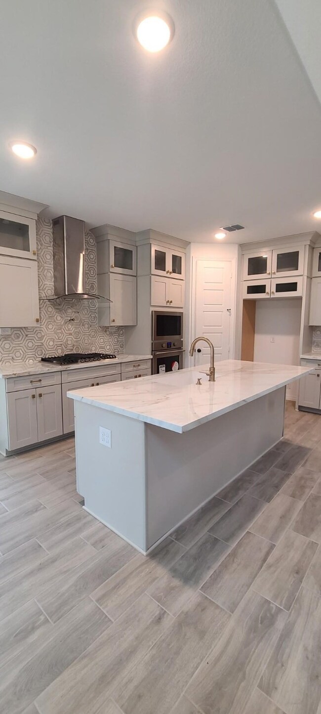 Lavish kitchen with porcelain countertops, large island, glass door cabinets, top of the line vent hood, 5 gas burner cook top and built in Micro/Oven.