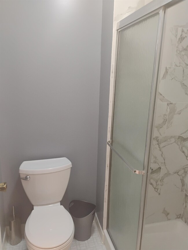 Bathroom featuring toilet, a stall shower, and baseboards