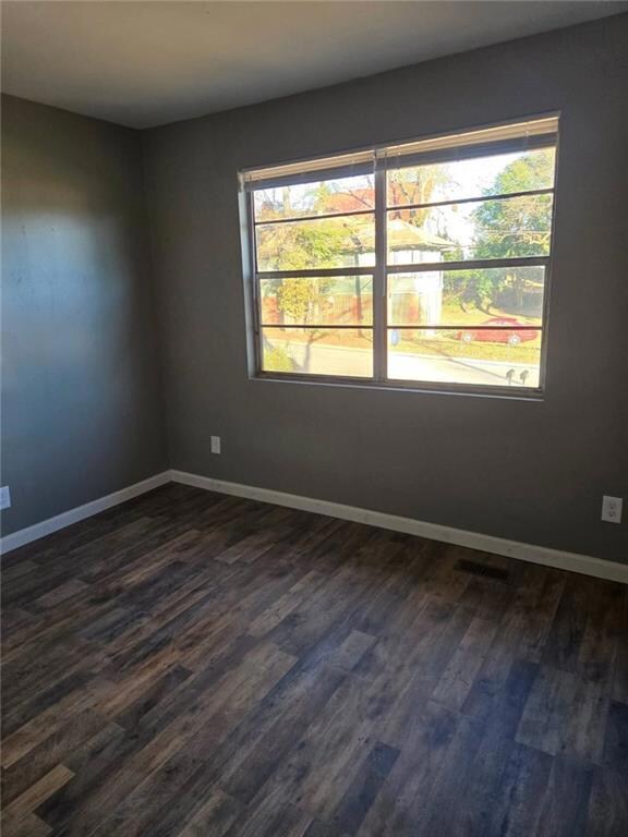 Unfurnished room with baseboards, visible vents, a