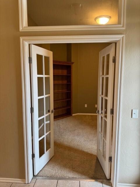 Hall with french doors, tile patterned floors, and carpet floors
