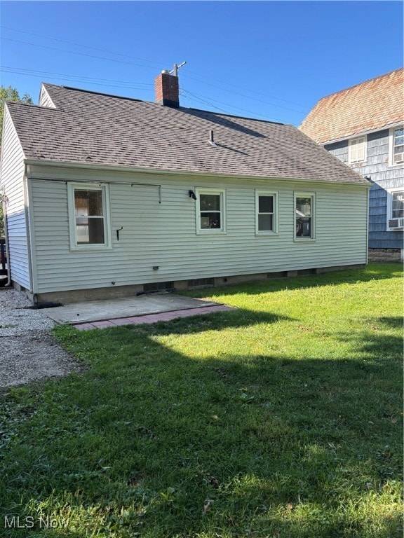 Back of property with a patio area, a shingled roof, a chimney, a lawn, and crawl space