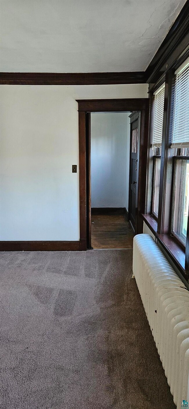 Corridor featuring dark colored carpet, radiator, 