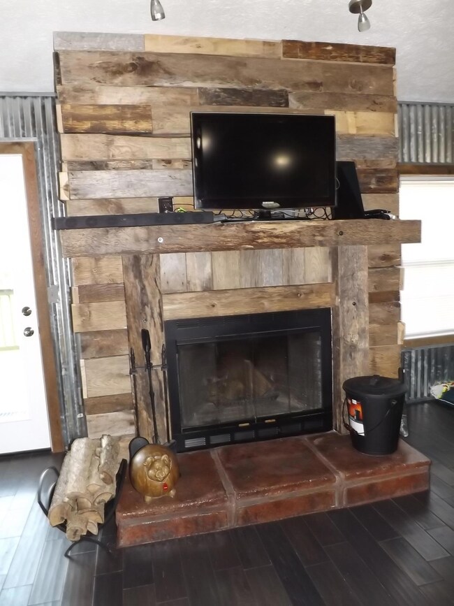 A closer view of the stunning barn-wood fireplace mantle with overhead lighting & wood burning fireplace.