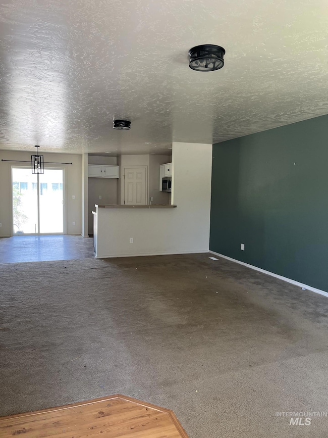 Unfurnished living room with a textured ceiling and carpet flooring