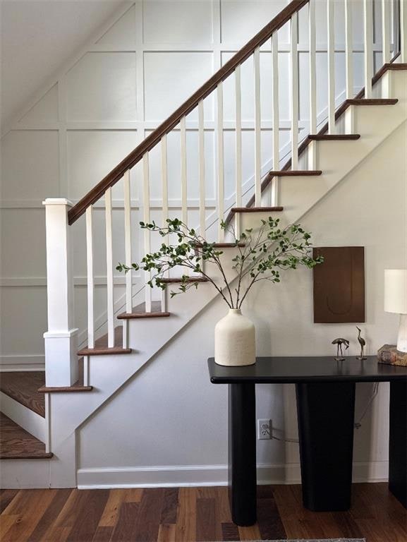 Staircase featuring wood finished floors and a decorative wall