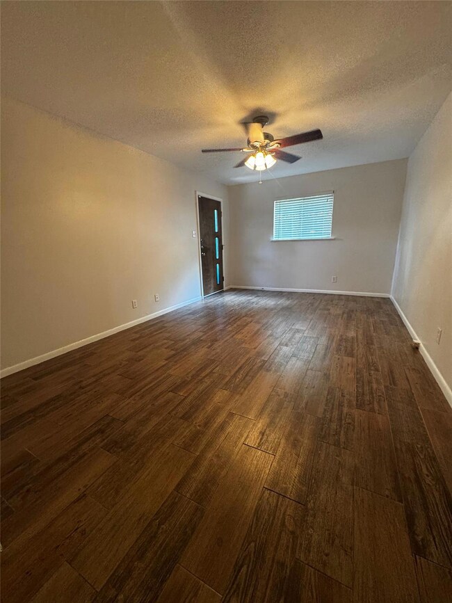 Unfurnished room with dark wood-style floors, a t