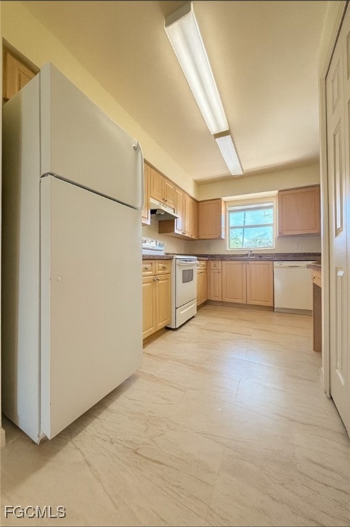 Kitchen with white appliances, light brown cabinets, and under cabinet range hood