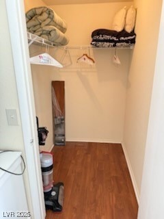 Walk in closet with dark wood-style floors