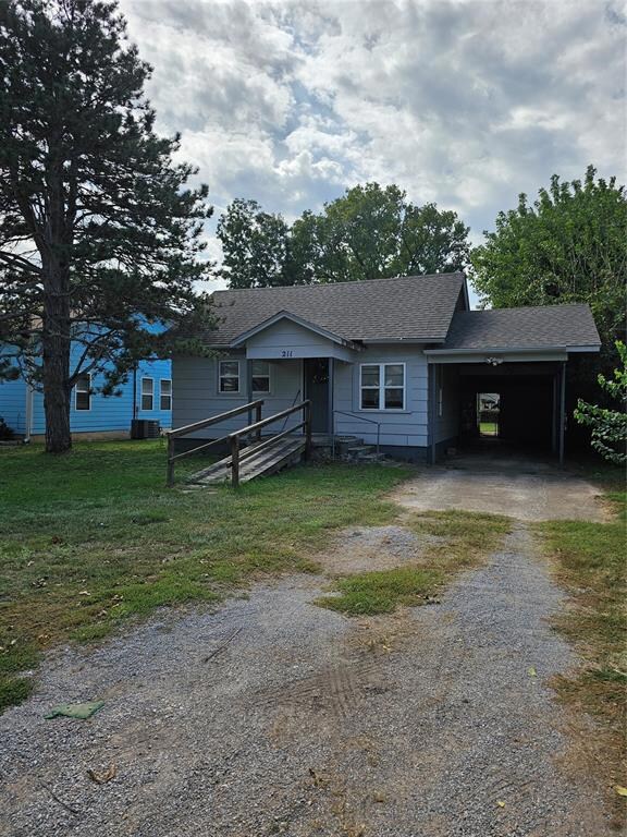 View of front facade featuring a carport, lawn