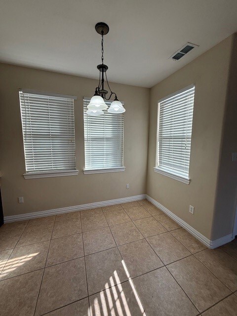 Unfurnished dining area featuring light tile patterned floors and a chandelier