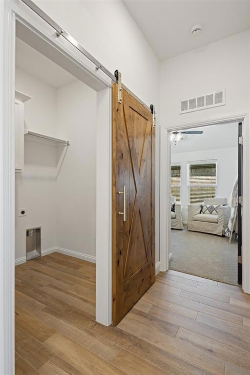 Corridor featuring a barn door and light hardwood 