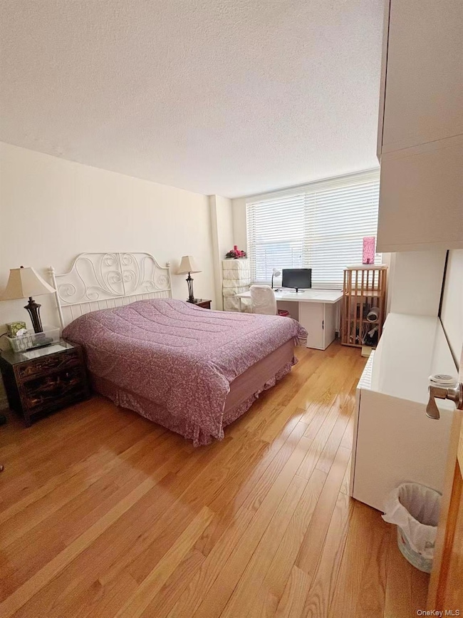 Bedroom with light wood-type flooring, a textured ceiling, and a desk