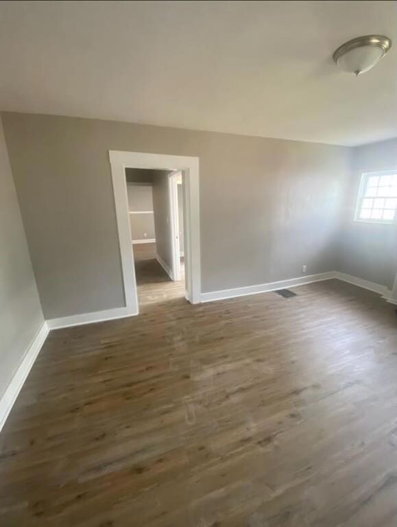 Unfurnished room with dark wood-style flooring and baseboards