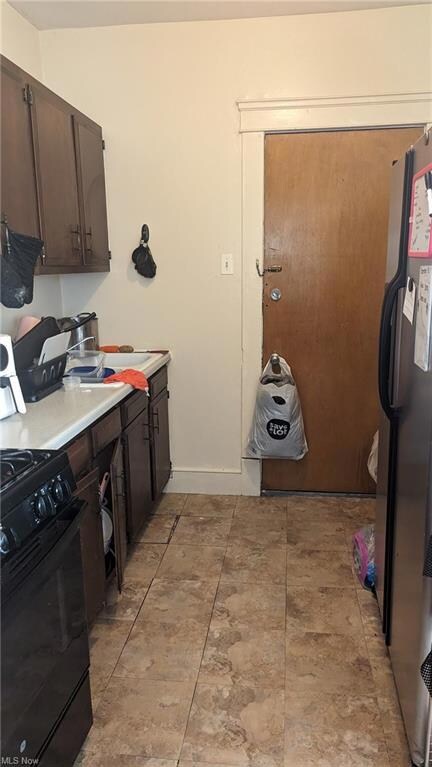 Kitchen featuring black appliances, light tile flooring, and dark brown cabinets