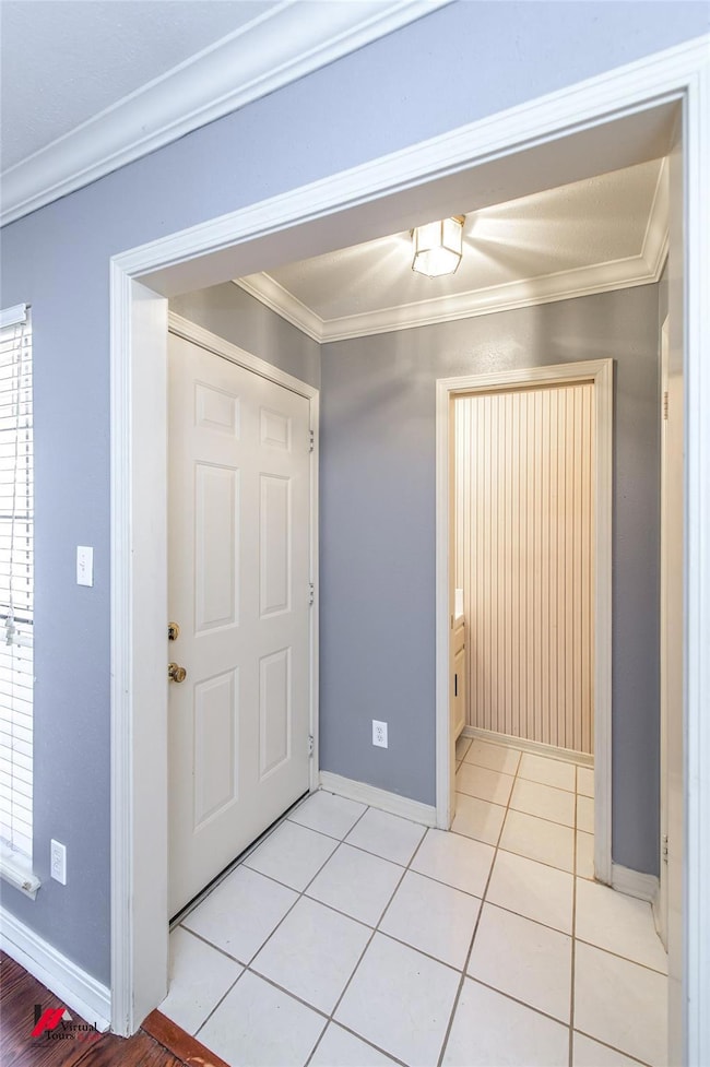Tiled foyer featuring ornamental molding