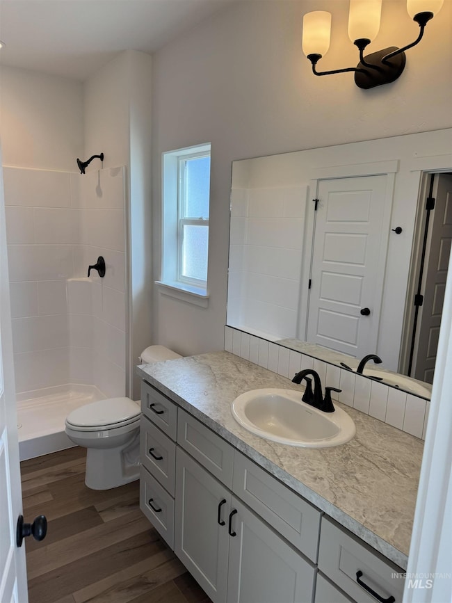 Full bath with vanity, dark wood finished floors, a shower stall, and a chandelier