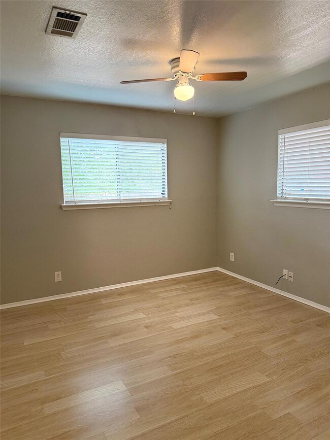 Empty room with ceiling fan, light wood-type floo
