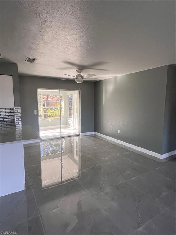 Spare room featuring ceiling fan and a textured ce