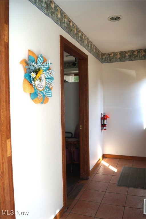 Hallway with tile patterned floors and baseboards