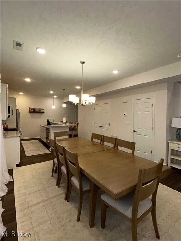 Dining space featuring a chandelier, dark wood-style flooring, recessed lighting, and a textured ceiling
