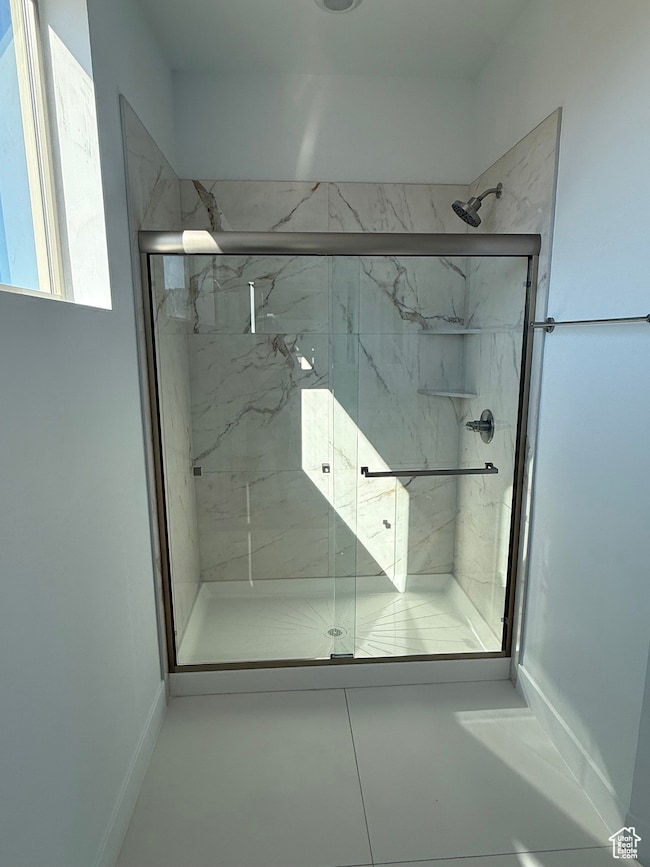 Bathroom featuring a marble finish shower and tile patterned flooring
